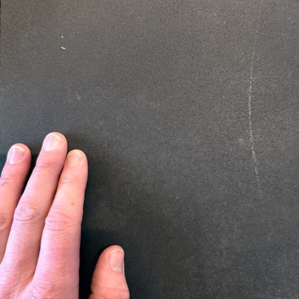 A hand resting on honed bluestone