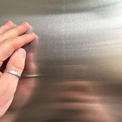 A hand on a brushed stainless drawer front
